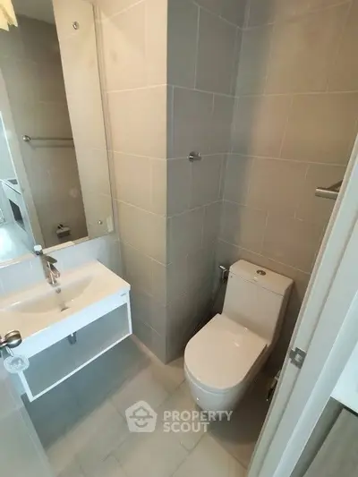 Modern bathroom with sleek design and compact layout, featuring a stylish sink and toilet.