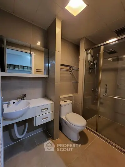 Modern bathroom with glass shower and sleek fixtures in contemporary apartment.