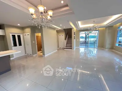 Spacious open-plan living area with elegant chandeliers and glossy tiled floors.