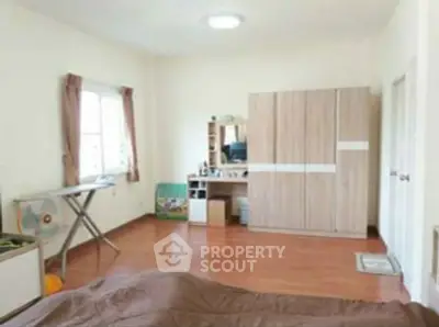 Spacious bedroom with wooden flooring and modern furniture