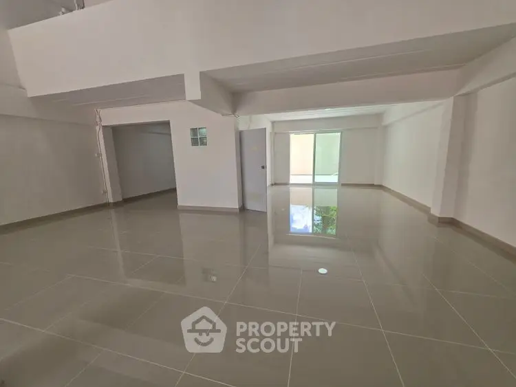 Spacious empty room with glossy tiled floors and large windows