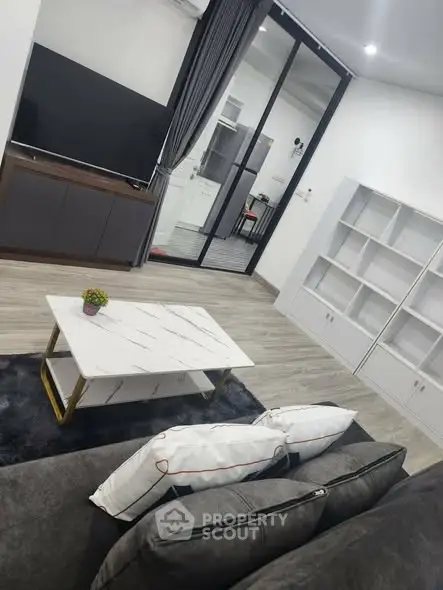 Modern living room with sleek furniture and large TV, featuring a stylish coffee table and elegant decor.