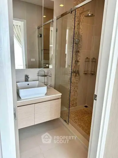 Modern bathroom with glass shower and stylish sink in a contemporary home.