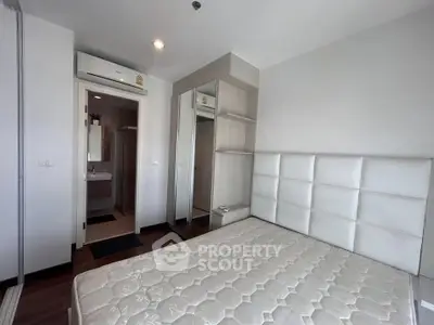 Modern bedroom with white padded headboard and mirrored wardrobe in a stylish apartment.