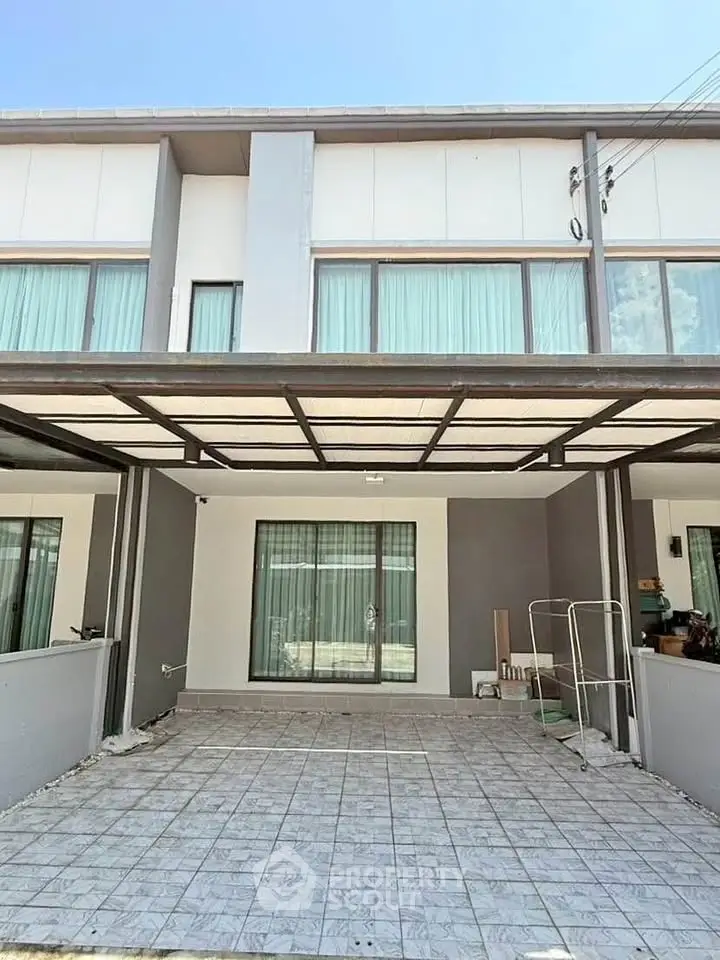 Modern townhouse with spacious tiled carport and large windows, perfect for family living.