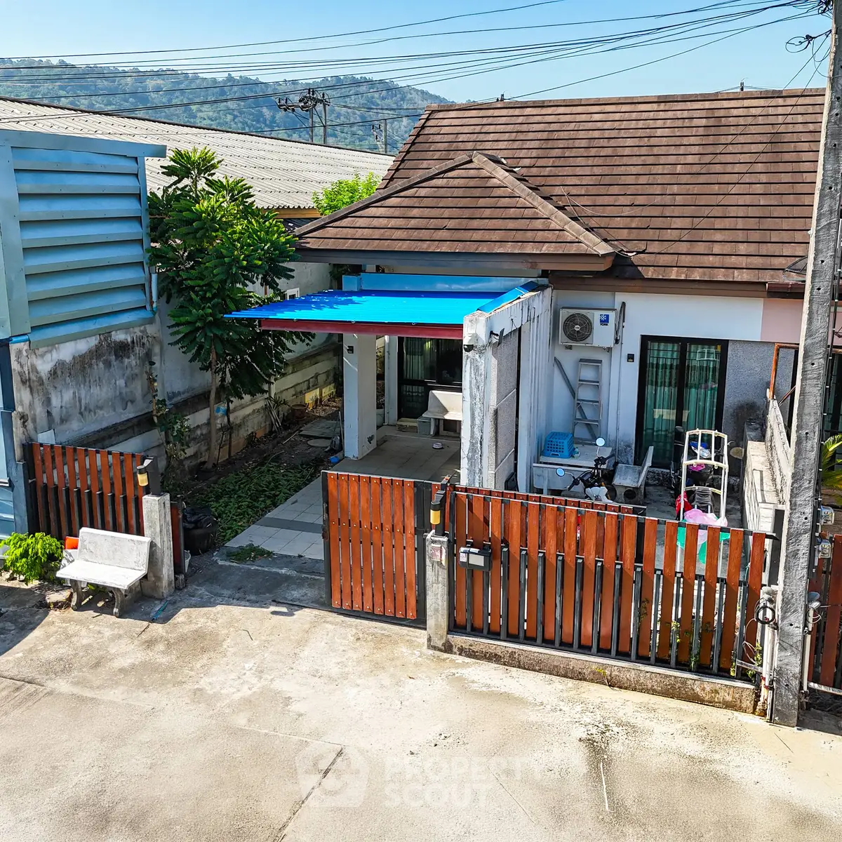 Charming single-story home with a tiled roof and gated entrance, featuring a cozy outdoor area and mountain views.