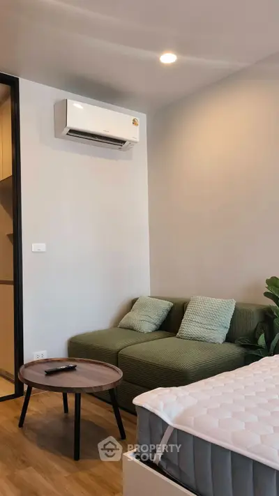 Modern bedroom with cozy green sofa and air conditioning, perfect for relaxation and comfort.