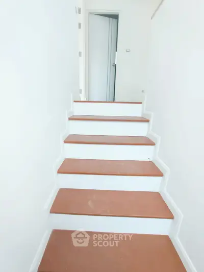 Modern staircase with sleek design and wooden steps leading to a bright interior space.
