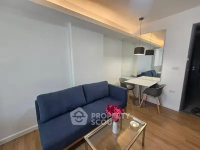 Modern living room with blue sofa, glass table, and dining area with mirror.