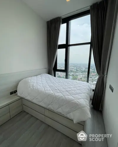 High-rise bedroom with panoramic city views through floor-to-ceiling windows, complemented by elegant dark drapes and modern minimalist decor.