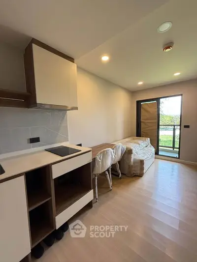 Modern open-layout living room with kitchen, featuring sleek cabinetry and natural light.