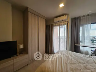 Modern bedroom with large window and city view, featuring a sleek wardrobe and air conditioning.
