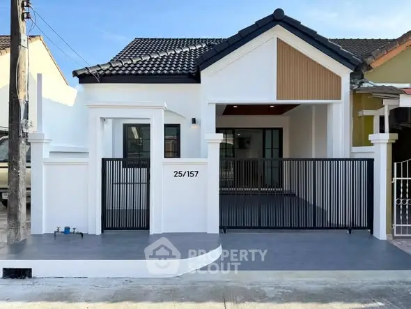 Charming modern house with sleek black and white exterior and gated entrance.