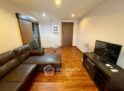 Spacious living room with modern leather sofa and flat-screen TV, perfect for relaxation.