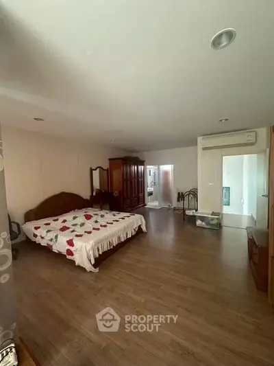 Spacious bedroom with wooden flooring and elegant furnishings in a modern home.