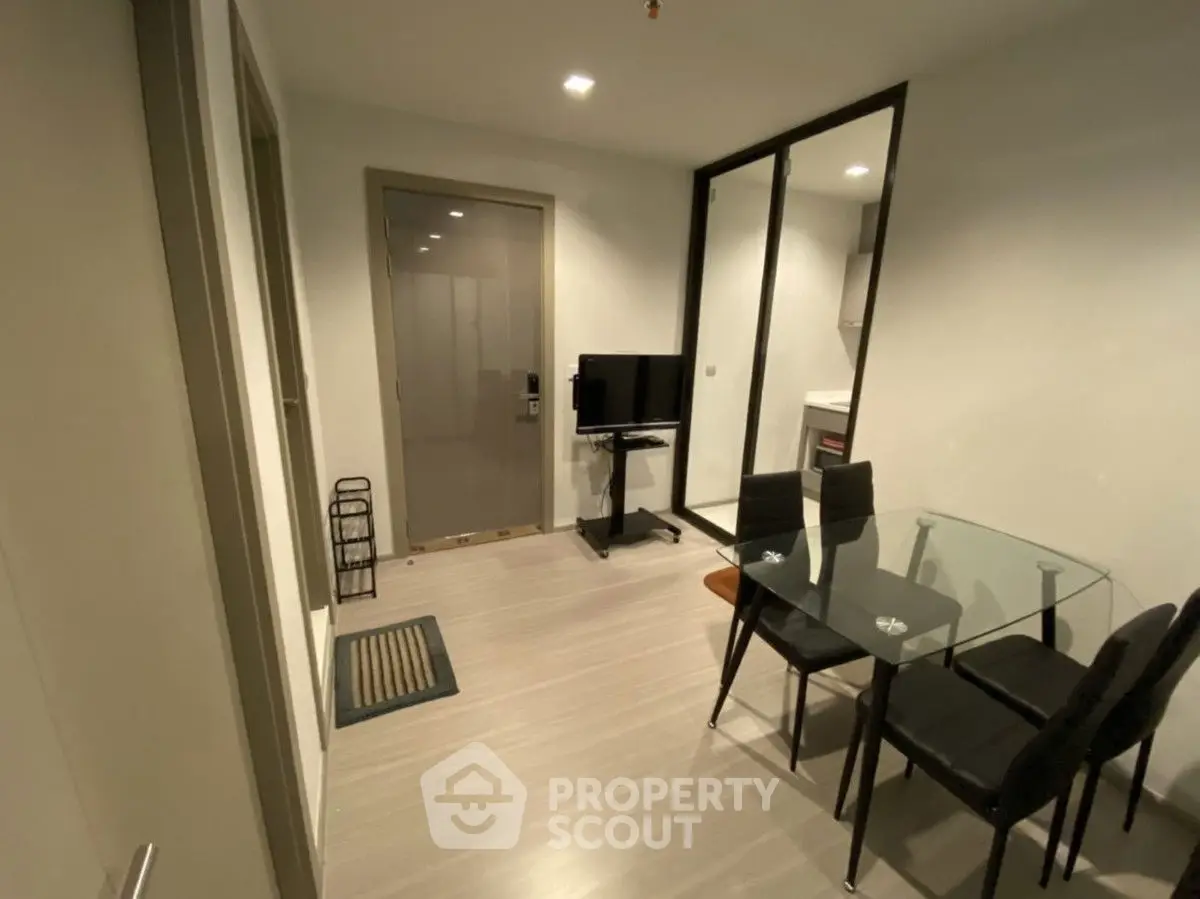 Modern apartment interior with glass dining table and TV, sleek minimalist design.