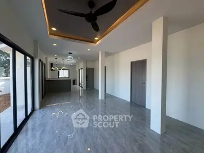 Spacious modern living room with sleek flooring and ceiling fan, perfect for contemporary living.