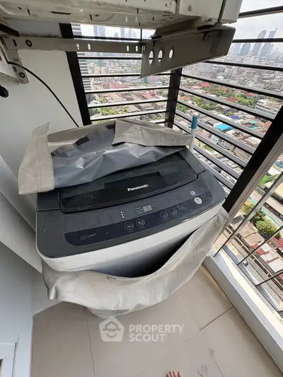 High-rise balcony with washing machine and city view, perfect for urban living convenience.