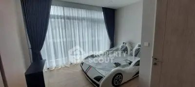 Charming bedroom with unique car-shaped bed and large window with elegant curtains.