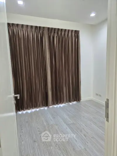 Spacious empty room with elegant curtains and modern flooring, perfect for customization.
