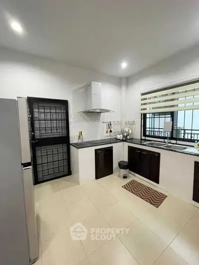 Modern kitchen with sleek design and ample natural light, featuring a closed layout and contemporary appliances.