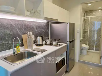 Modern kitchen with sleek appliances and adjacent bathroom, featuring a stylish open layout and contemporary design.