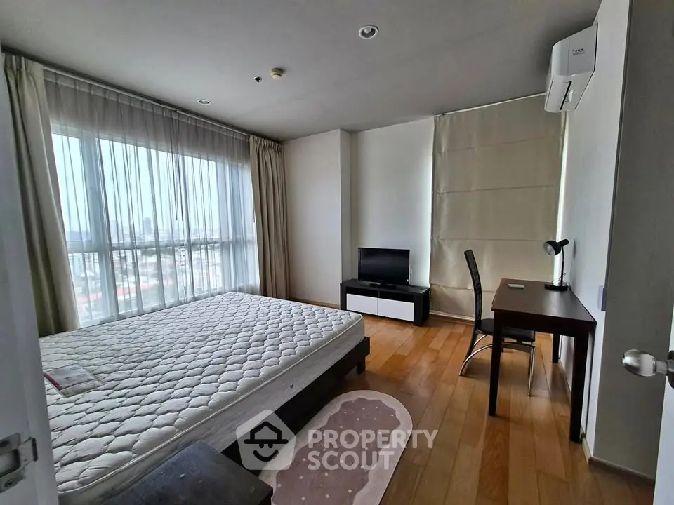 Spacious bedroom with large window and wooden flooring in modern apartment
