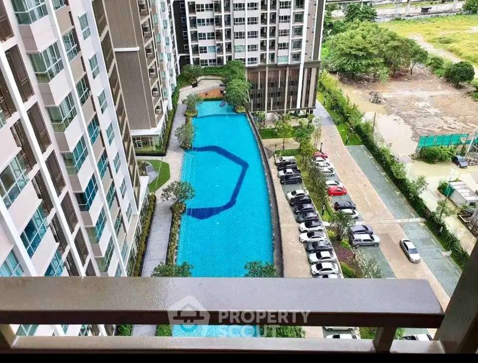 Stunning aerial view of modern condominium with large swimming pool and lush surroundings.