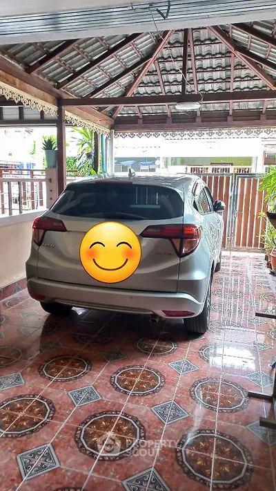 Covered parking area with tiled floor and parked car in residential property.