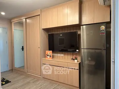 Modern living room with built-in wooden cabinets and stainless steel fridge