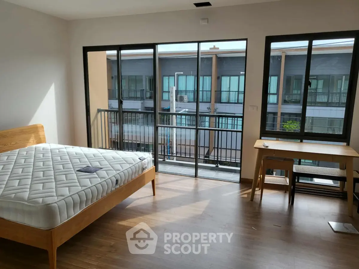 Spacious bedroom with large windows and balcony access in modern apartment.