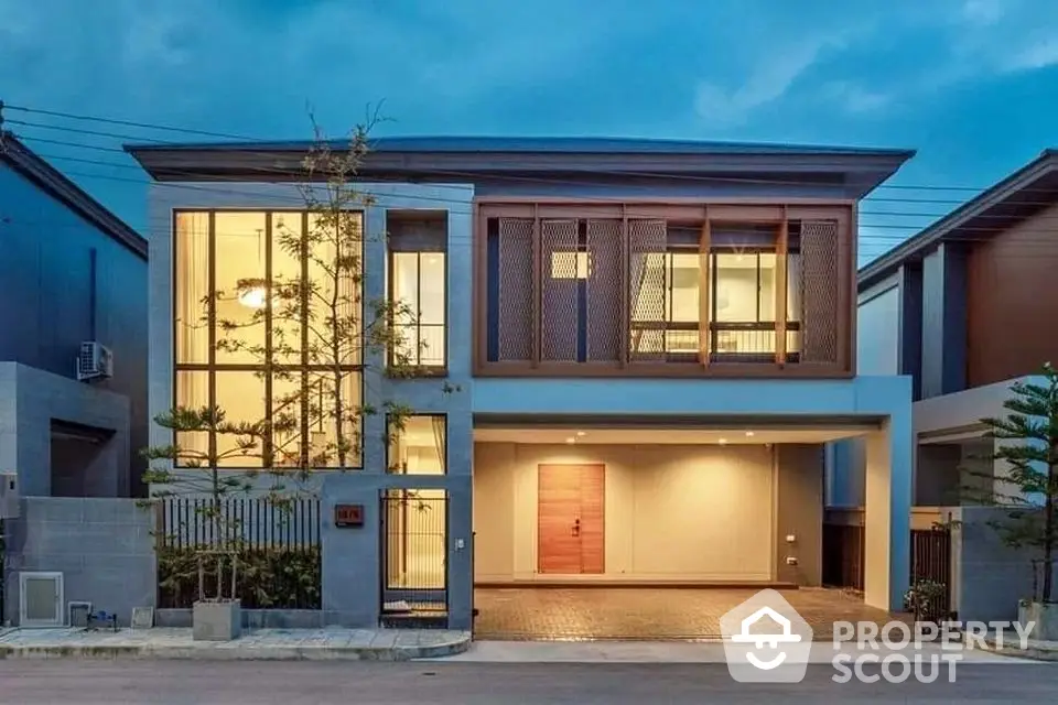 Modern two-story house with large windows and elegant facade at dusk