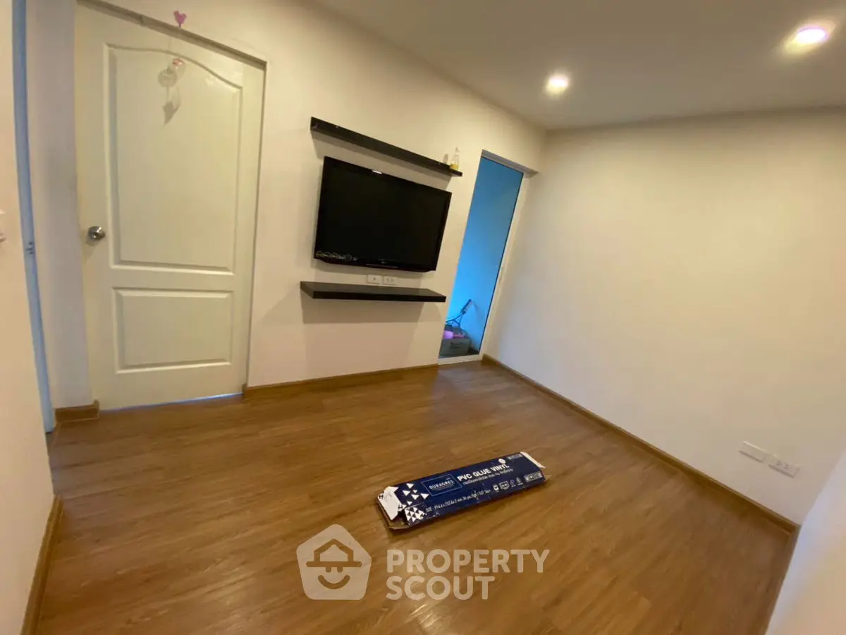 Modern living room with wooden flooring and wall-mounted TV, ready for customization.
