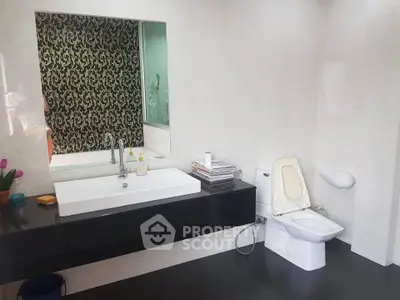 Modern bathroom with sleek black and white design, featuring a large mirror and contemporary fixtures.