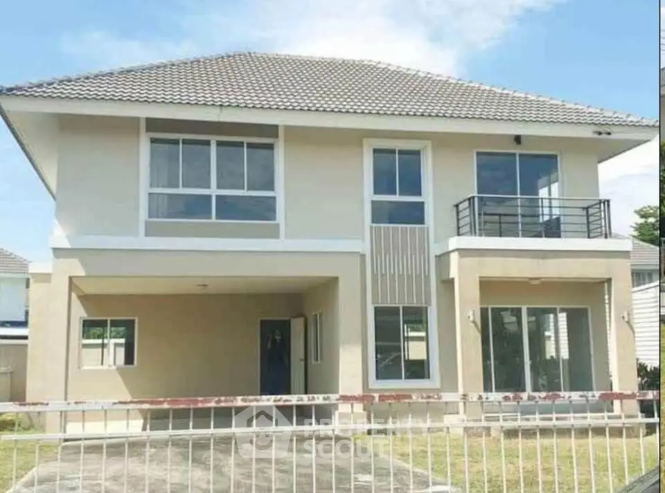 Modern two-story house with balcony and large windows, perfect for family living.