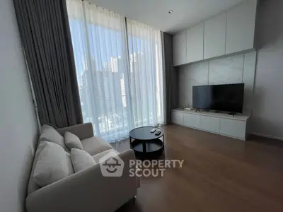 Modern living room with large windows and city view, featuring sleek furniture and a flat-screen TV.