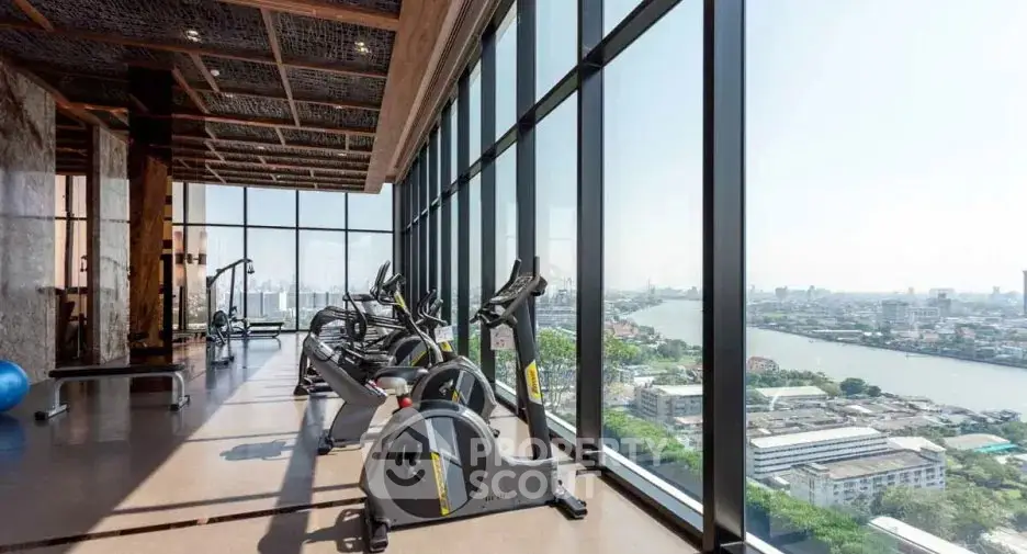 Luxurious high-rise gym with panoramic city and river views, featuring modern exercise equipment and floor-to-ceiling windows.