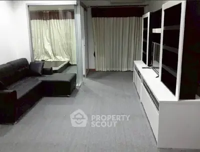 Spacious living room with modern black sofa and sleek entertainment unit.