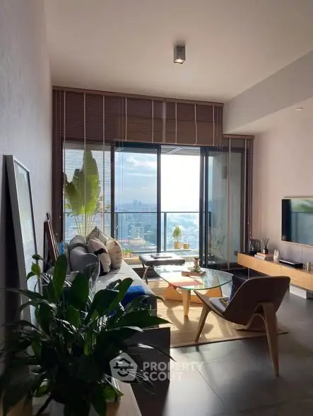 Modern living room with large windows and city view, featuring stylish furniture and decor.