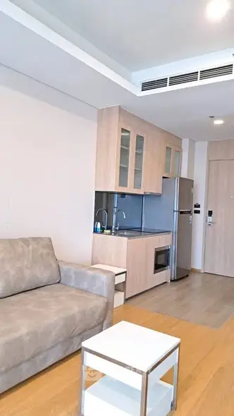 Modern apartment interior with compact kitchen and cozy living area, featuring sleek appliances and stylish furniture.