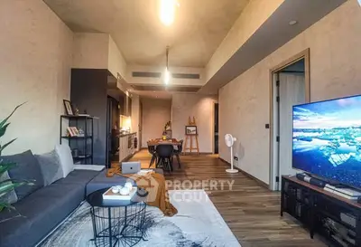 Modern living room with open kitchen, stylish decor, and large TV in a contemporary apartment.