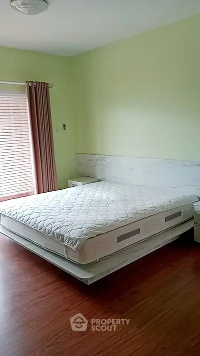 Spacious bedroom with modern design and natural light, featuring a comfortable bed and elegant decor.