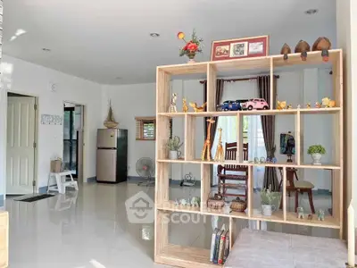 Spacious living room with modern decor and natural light, featuring a stylish open shelf and elegant furnishings.