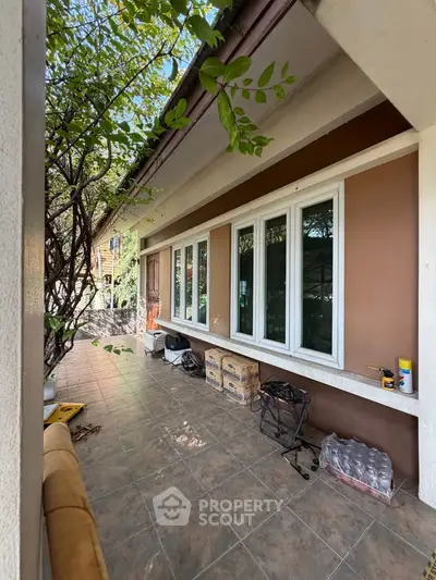 Charming garden view with spacious tiled balcony and lush greenery, perfect for relaxation.