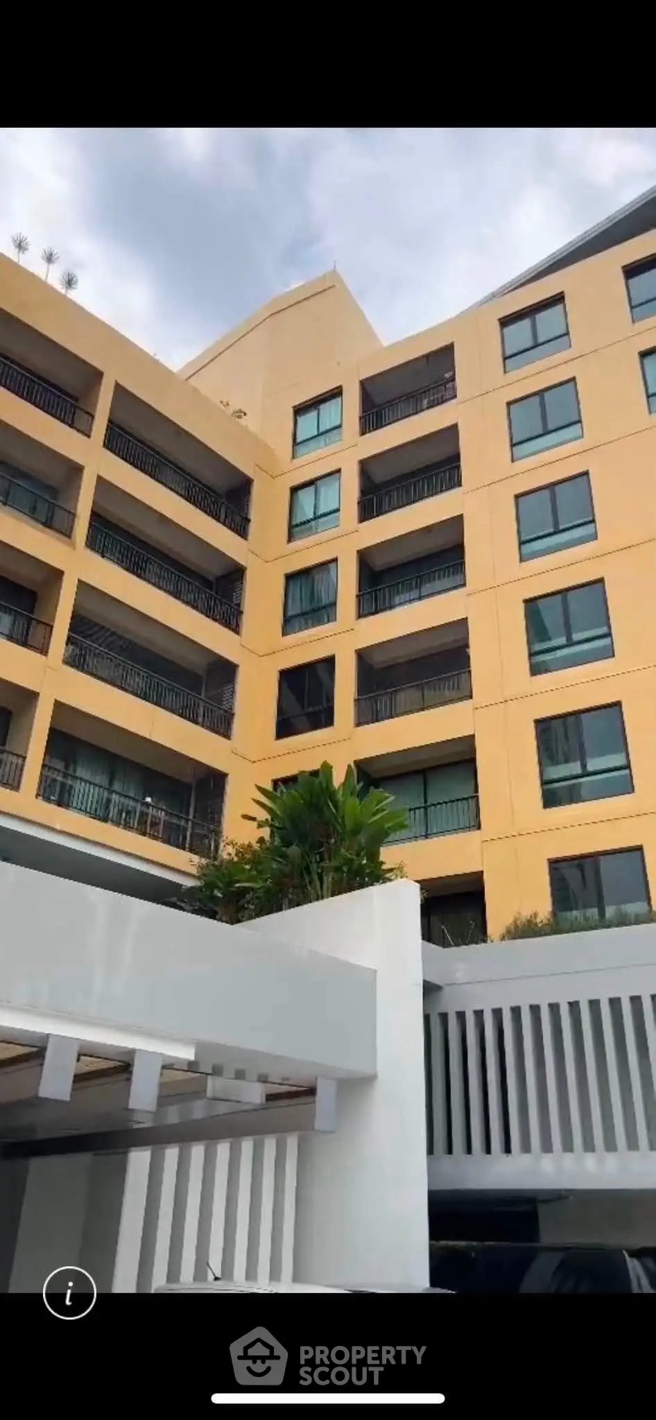 Modern multi-story apartment building with balconies and lush greenery, ideal for urban living.