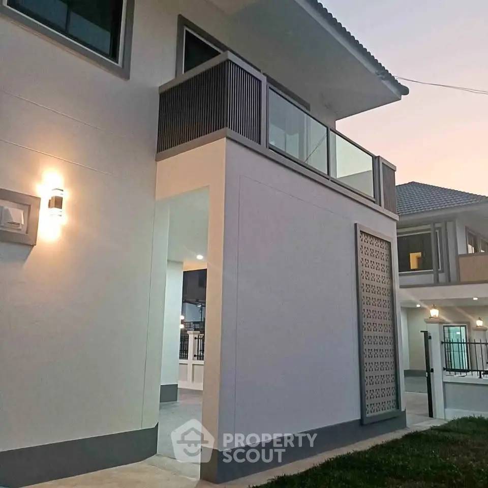 Modern two-story house exterior with balcony and stylish lighting at dusk.