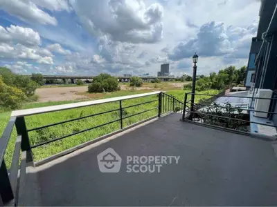 Spacious balcony with scenic view of greenery and city skyline, perfect for relaxation.