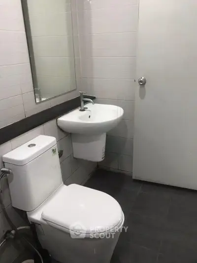 Modern bathroom with sleek fixtures and minimalist design, featuring a wall-mounted sink and toilet.