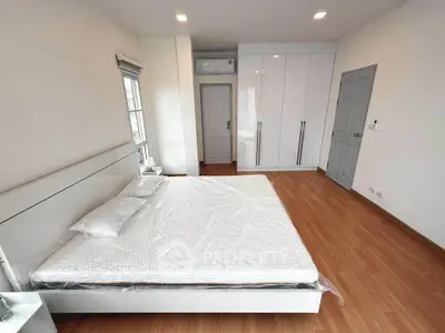 Spacious modern bedroom with wooden flooring and large wardrobe