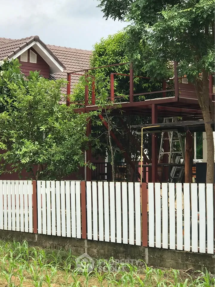 Charming red wooden house with white picket fence and lush greenery